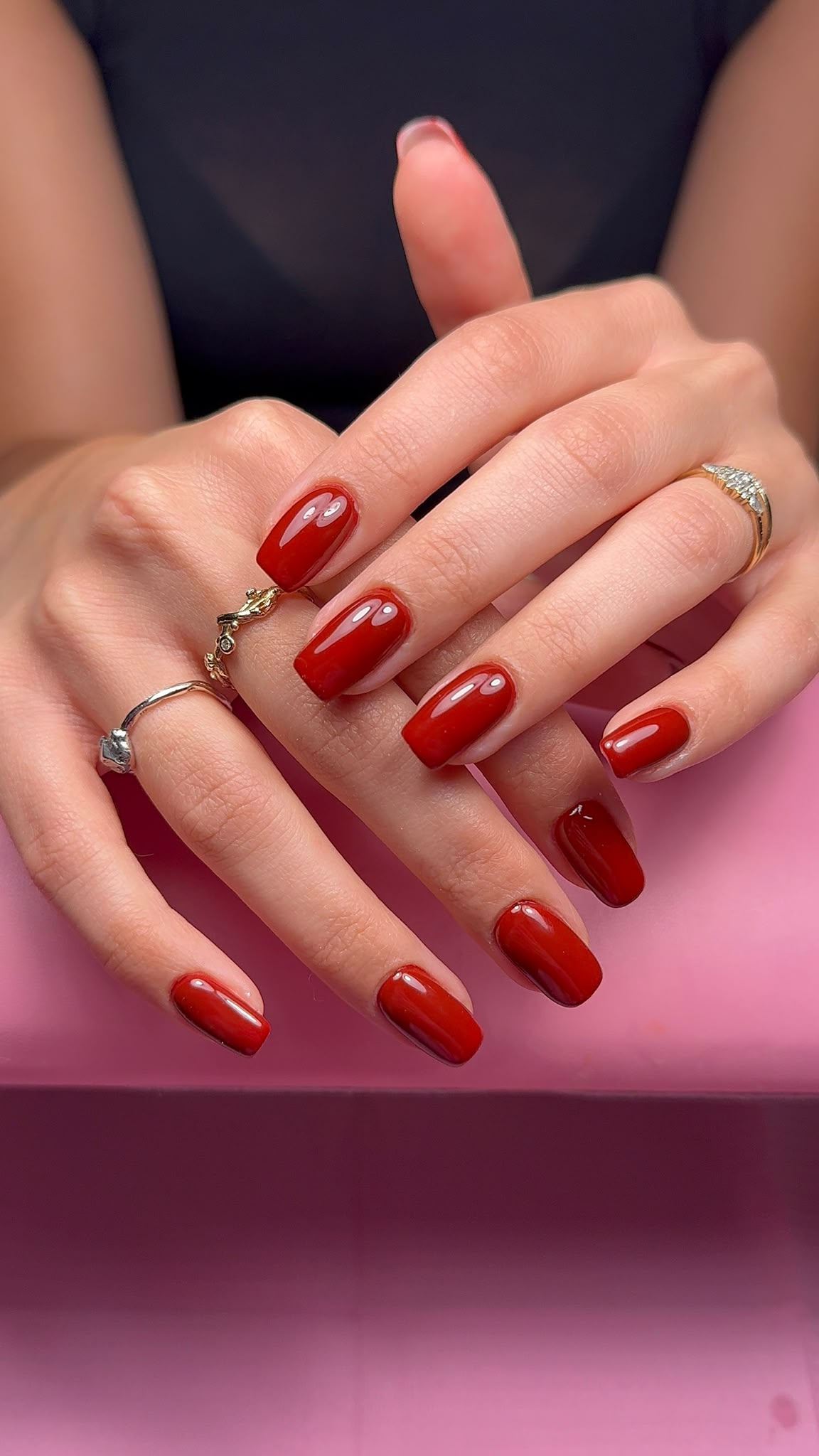 Glossy cherry red square nails photographed on a client hand