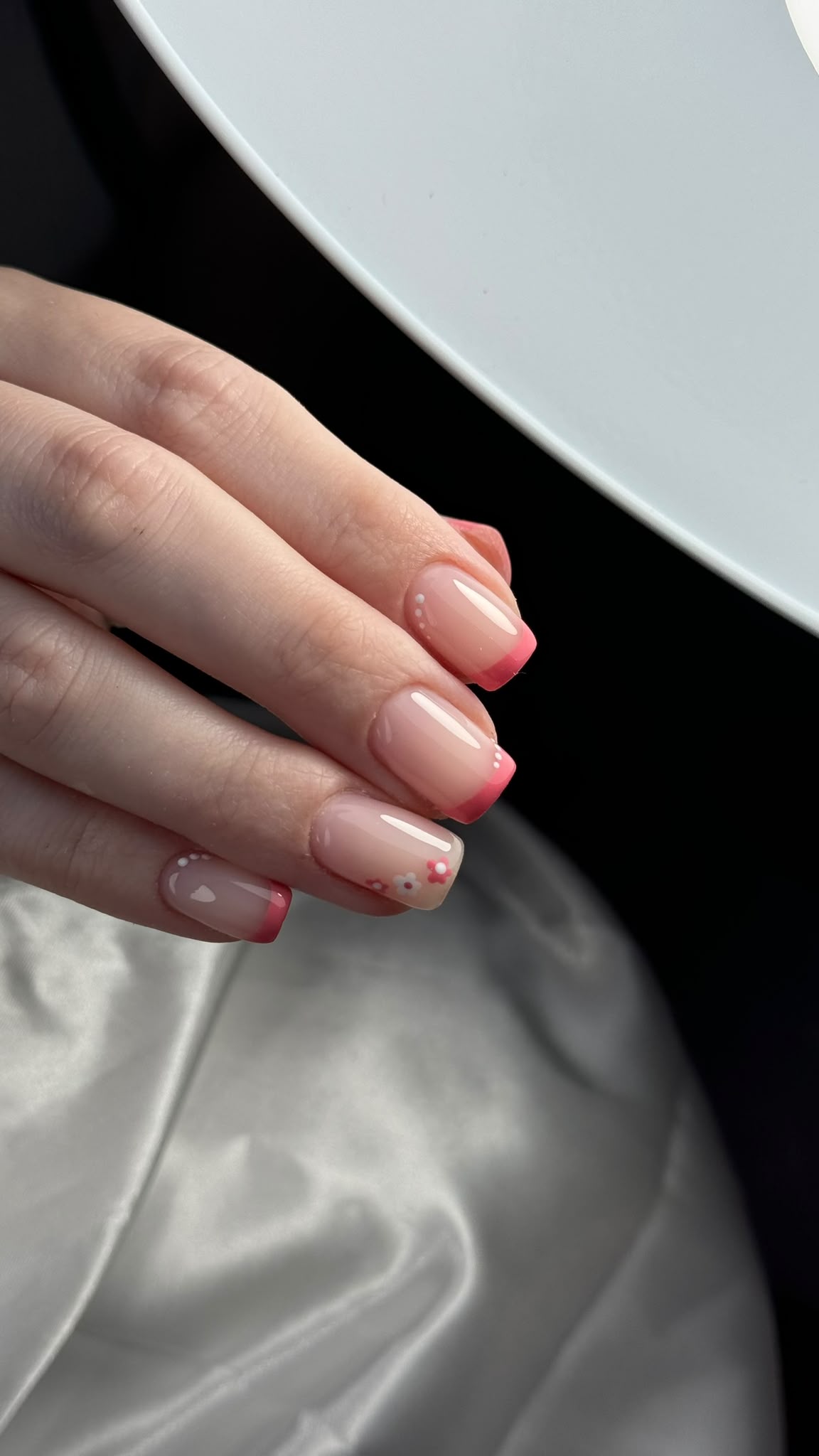 Pink negative-space French nails with tiny floral details