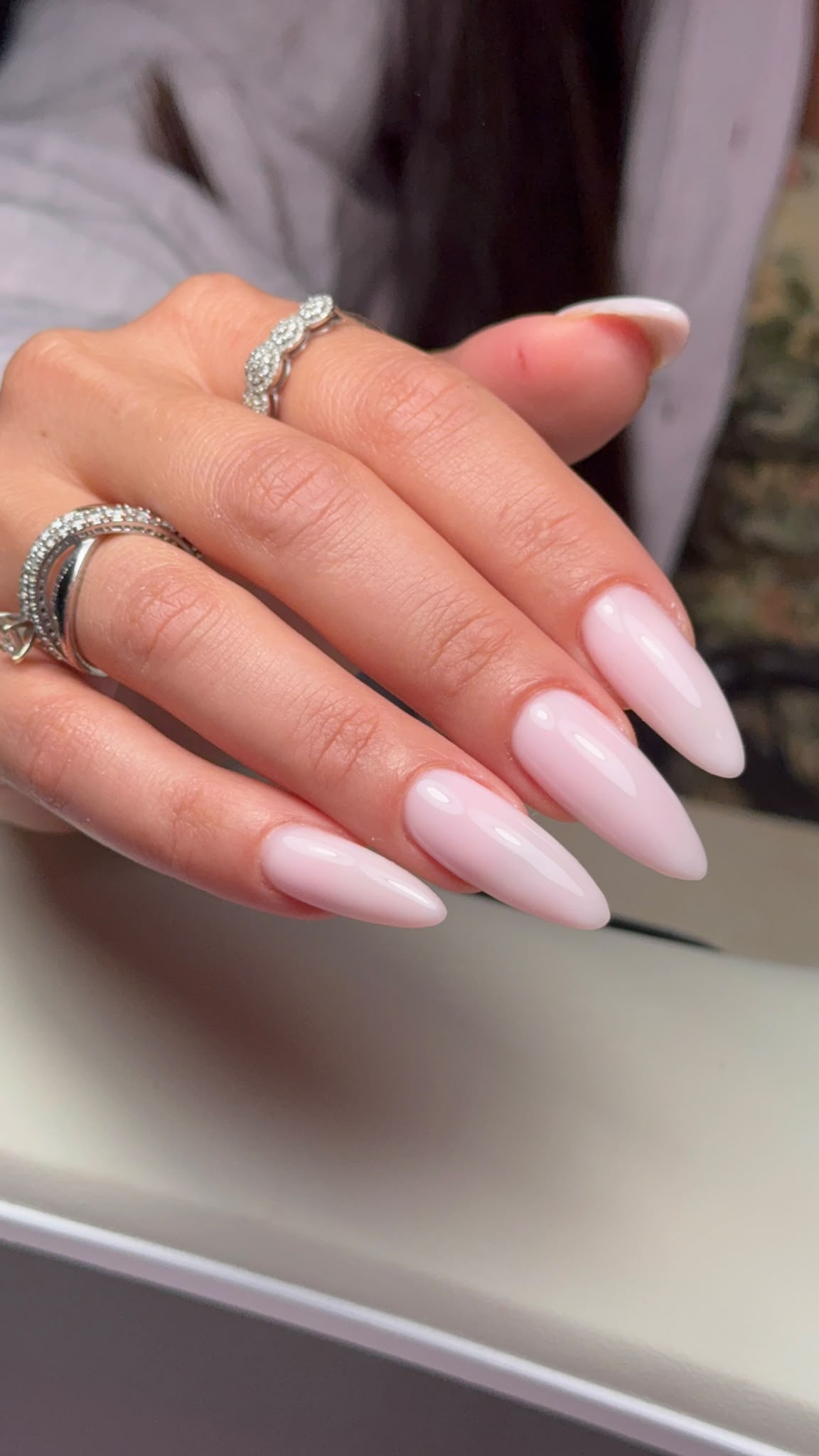 Milky pink almond-shaped nails photographed on a client hand